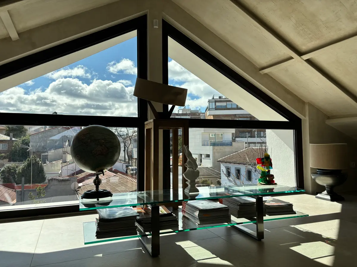 Estudio bajo cubierta con ventanal triangular.