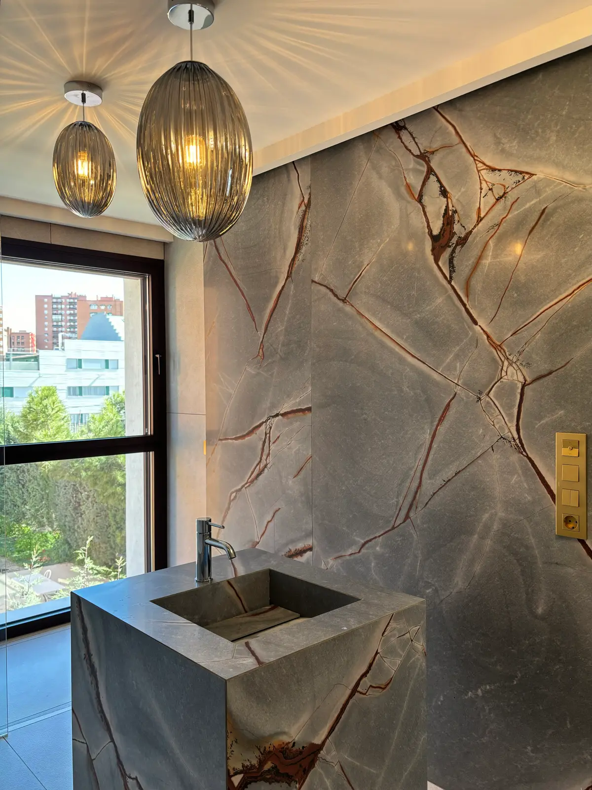Baño con lavabo de piedra y pared de mármol.
