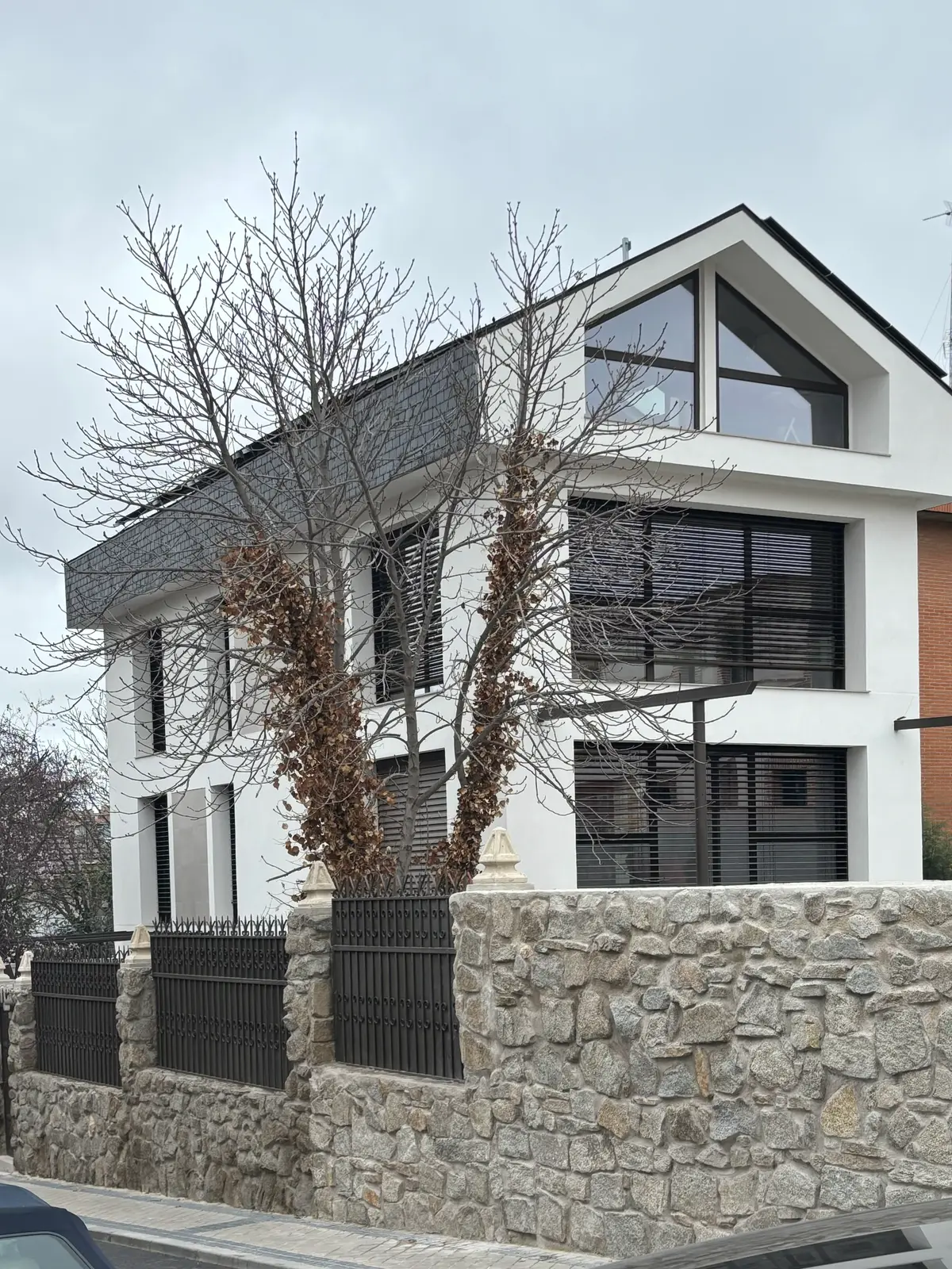 La casa desde la calle, sobre el muro de piedra.