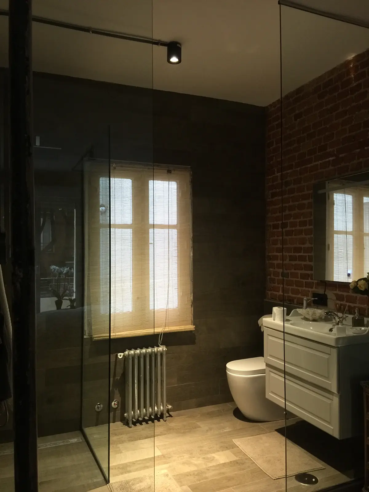 Baño con ventana de madera y pared de ladrillo.