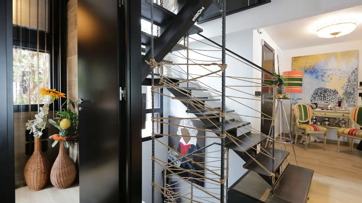 Escalera de acero y peldaños de madera junto al ventanal.